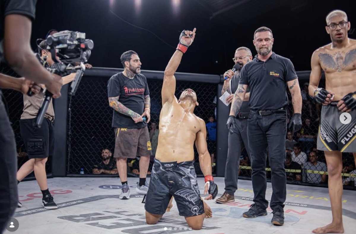 Warlen Samuray de joelhos no ringue, apontando para o céu após uma vitória